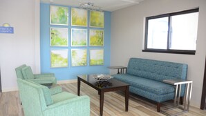 A room with a blue sofa, two green armchairs, a wooden coffee table, and a small side table. - Days Inn by Wyndham Le Roy/Bloomington Southeast (Le Roy)