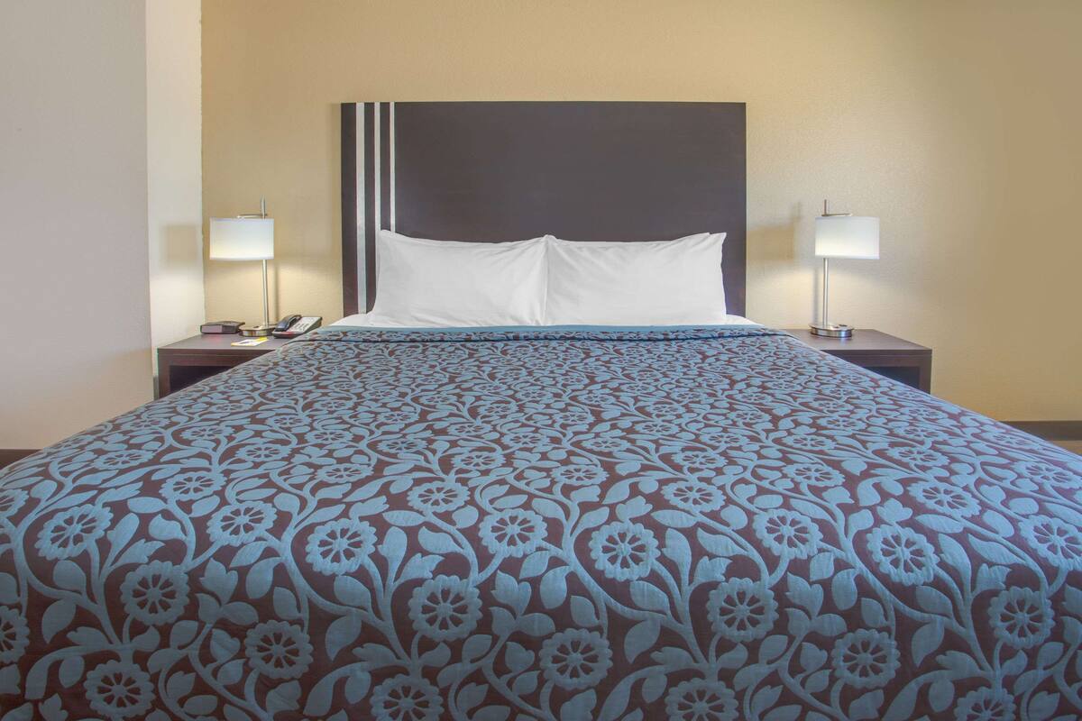 A hotel room with a large bed, two bedside tables, and two lamps.