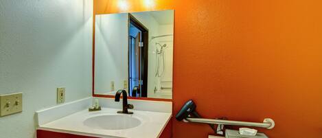 A bathroom with a white sink, a mirror, and a towel rack.