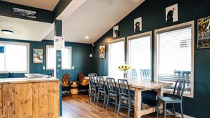 A dining area with a wooden table and chairs, a wooden counter, and a window with blinds. - Loyal Duke Lodge (Salida)
