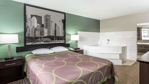 A hotel room with a bed, a large cityscape painting, a bathtub, and a window with curtains.