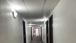 Un pasillo largo y estrecho con paredes blancas y alfombra oscura.