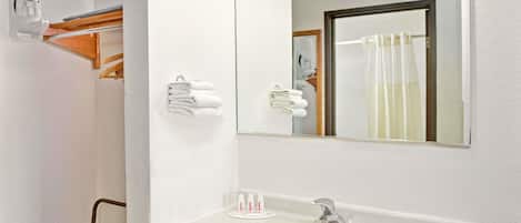 Un baño con lavamanos, espejo, toallero y tabla de planchar.