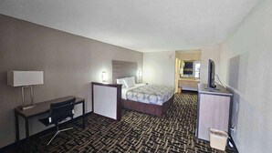 A hotel room with a bed, desk, chair, lamp, TV, and a bathroom visible through an open door. - Motel 6 Litchfield, IL (Litchfield)