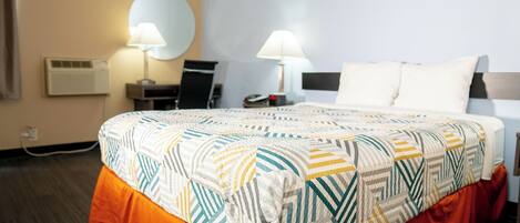 Una habitación de hotel con una cama, dos lámparas de noche, un escritorio y una silla.