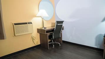 Habitación de hotel con escritorio, silla, lámpara, unidad de aire acondicionado y una gran proyección en la pared.