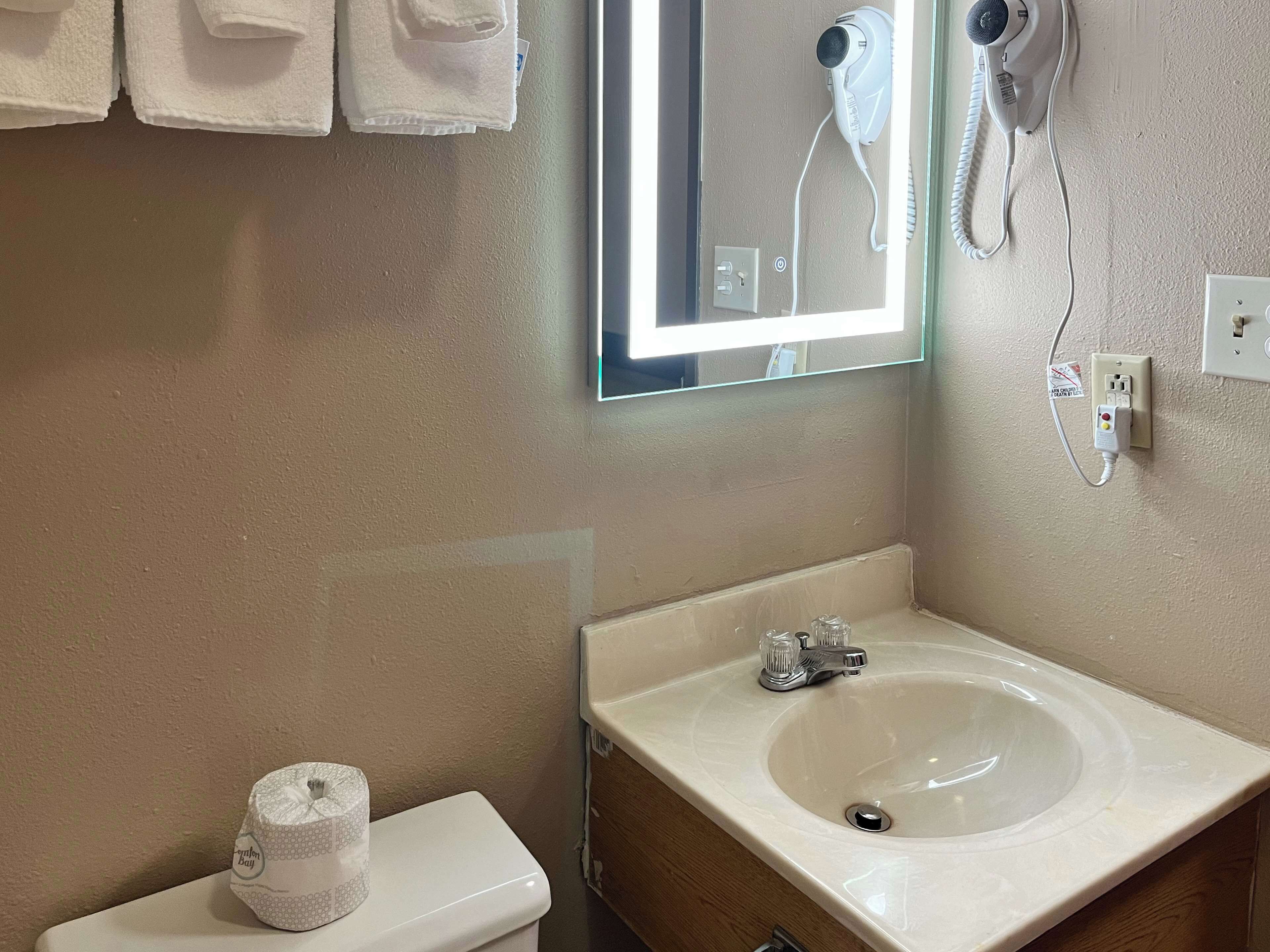 A bathroom with a toilet, a sink, and a hairdryer mounted on the wall.
