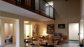 A spacious lobby with multiple seating areas, a staircase, and a bookshelf filled with magazines. - Super 8 by Wyndham Bentonville (Bentonville)