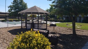 A gazebo with a roof, surrounded by gravel and a small bush. - Super 8 by Wyndham Bentonville (Bentonville)