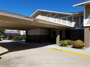 A building with a covered entrance, a sign indicating a 6-ft clearance, and two 'WELCOME' signs. - Super 8 by Wyndham Bentonville (Bentonville)