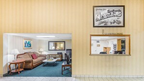 A hotel lobby with a reception desk, a sofa, a coffee table, and a framed welcome sign. - Super 8 by Wyndham Bentonville (Bentonville)