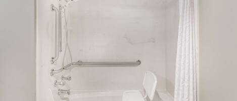 Una ducha blanca con una barra de apoyo, una silla blanca y una bañera.