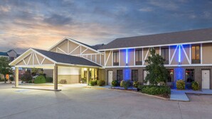 A hotel with a covered entrance, multiple windows, and a brick facade. - Super 8 by Wyndham Bentonville (Bentonville)