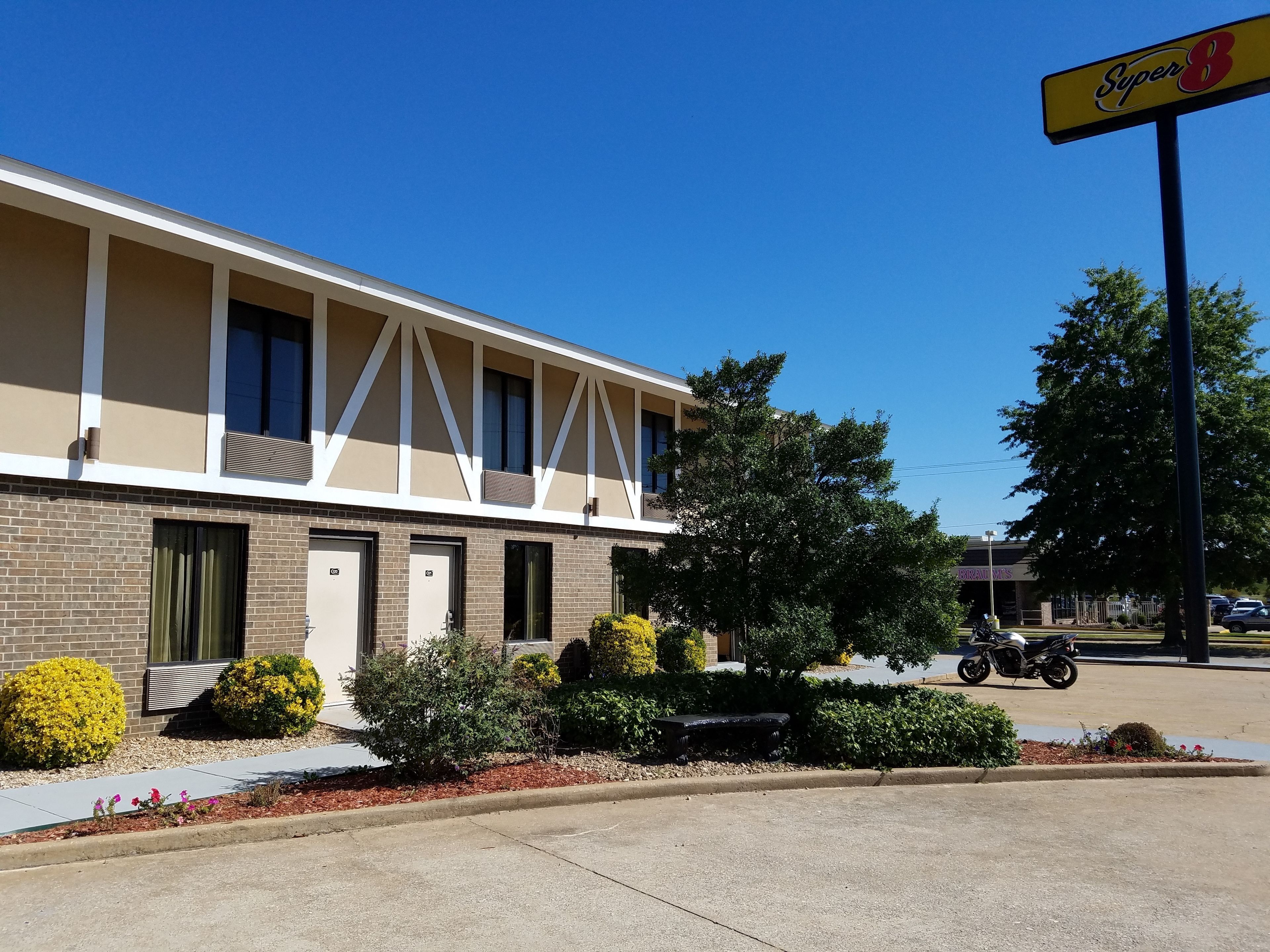 A motel with a row of rooms, a covered parking area, and a Super 8 sign.