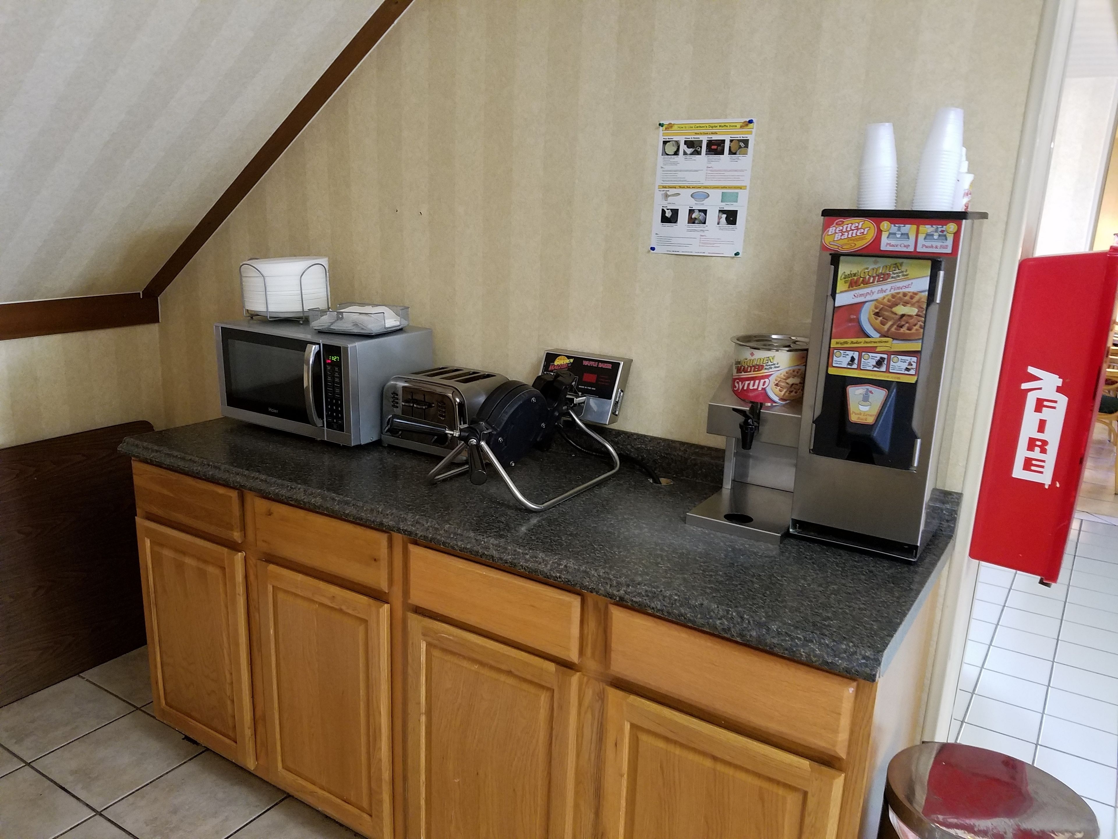 Una cocina equipada con microondas, tostadora y dispensador de sirope.