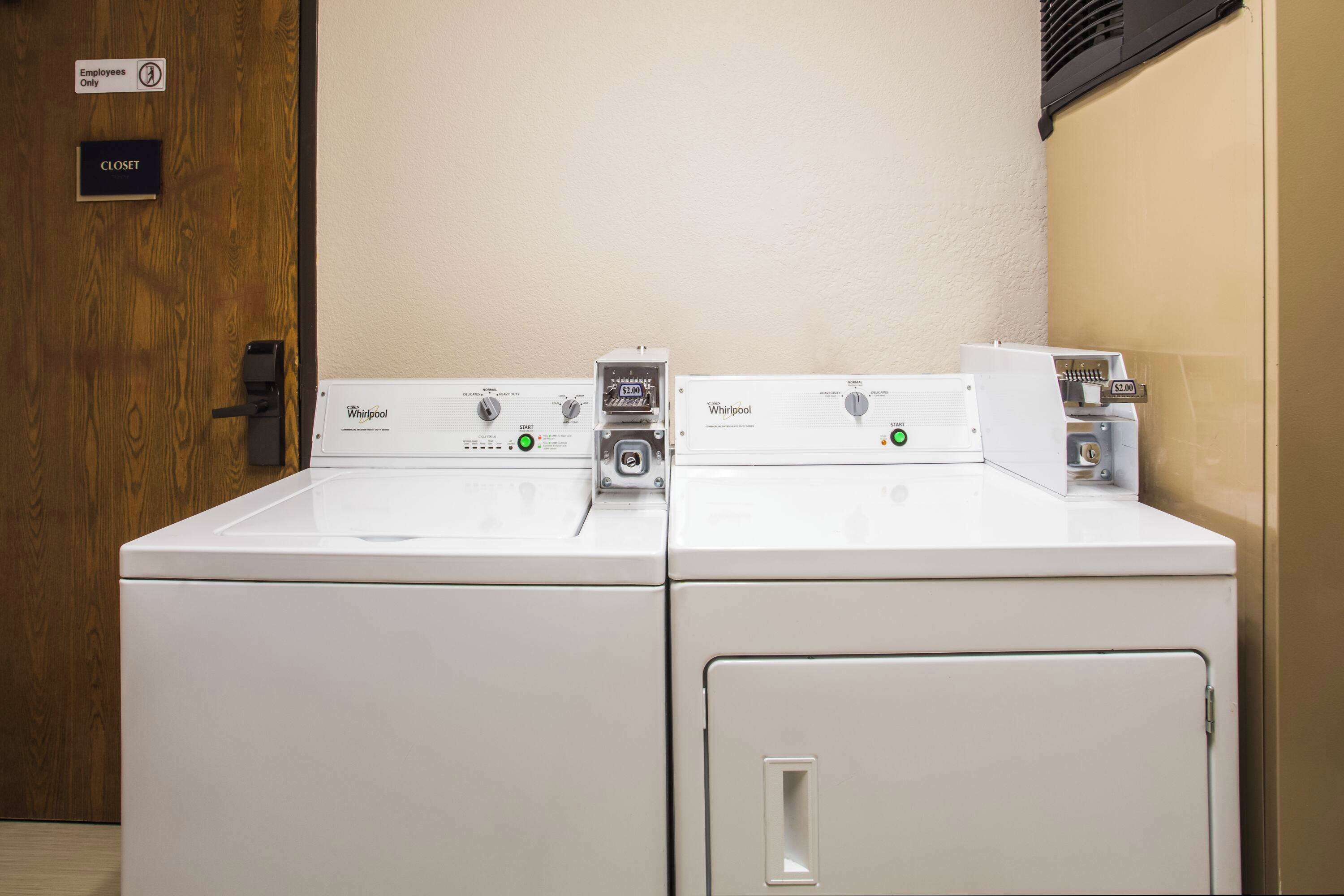 A laundry area with two Whirlpool washers and a coin-operated dryer.