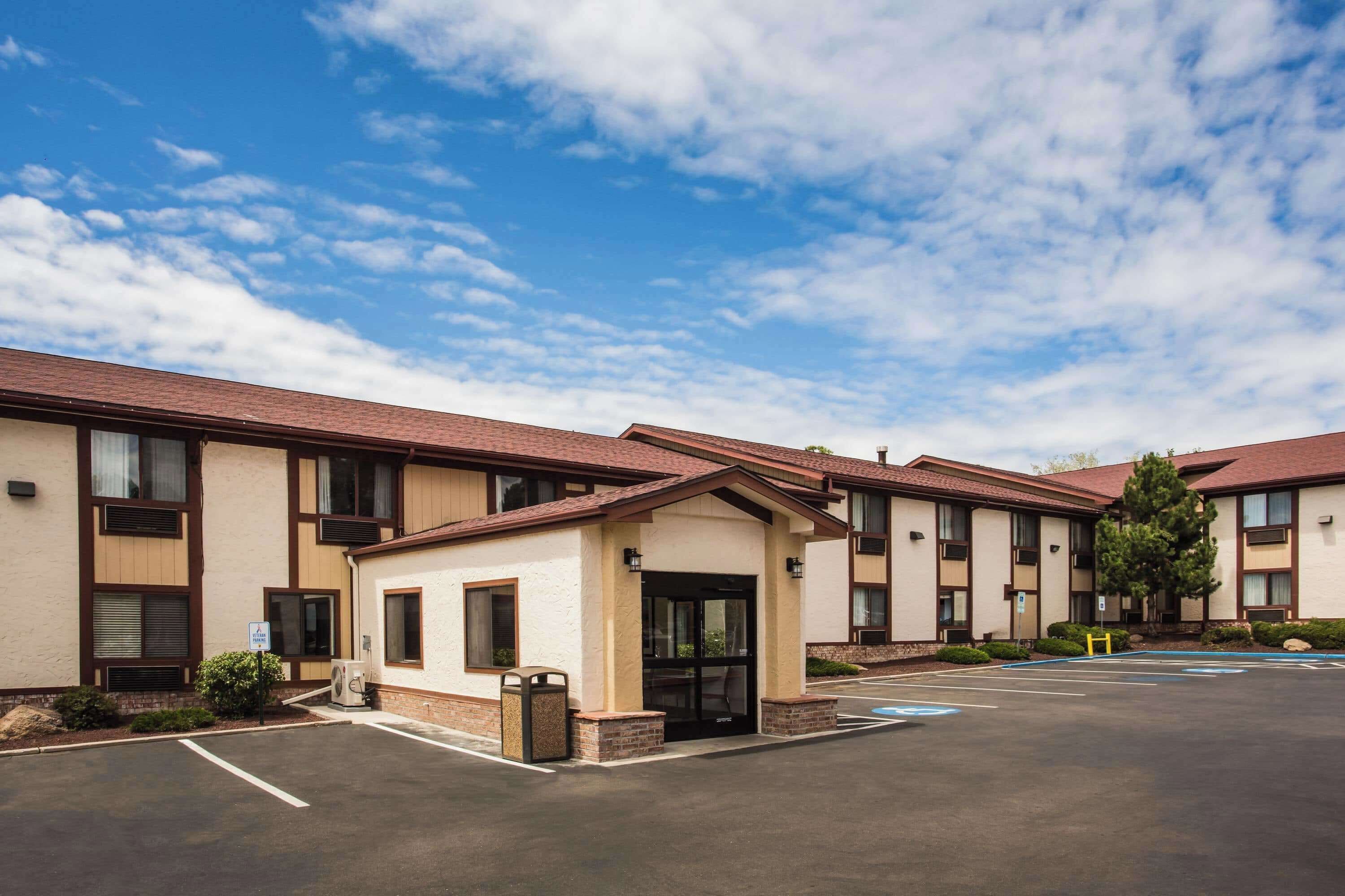 Un hotel con estacionamiento, varias construcciones y cielo despejado.