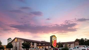 A motel with a large 'Super 8' sign, multiple parking spaces, and a clear sky.