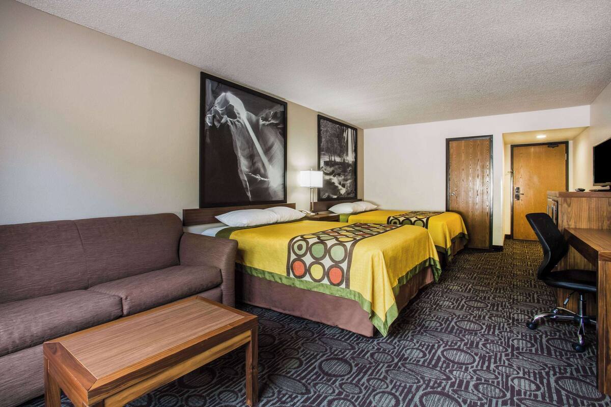 Habitación de hotel con dos camas, un sofá, un escritorio y un televisor.