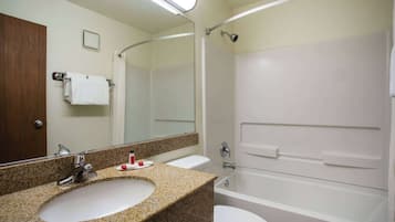A bathroom with a granite countertop sink, a white toilet, a bathtub, and a mirror.