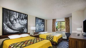 Ein Hotelzimmer mit zwei Betten, einem Schreibtisch, einem Stuhl, einem Fernseher und einem Fenster mit Vorhängen.