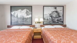 A hotel room with two beds, a nightstand with a lamp, and two framed pictures on the wall. - Super 8 by Wyndham Grand Junction Colorado (Grand Junction)