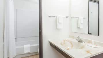 Un baño con ducha, un lavabo con encimera de mármol y un espejo sobre el lavabo.