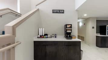 Un bar de café con un letrero encima, una máquina de café y varios artículos relacionados con el café en la barra.