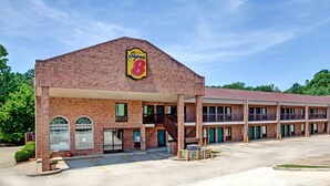 Un motel de type Super 8 avec une façade en briques, de nombreux balcons et un parking.