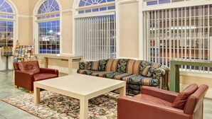 Un hall d’entrée avec un canapé, deux fauteuils, une table basse et un tapis à motifs.