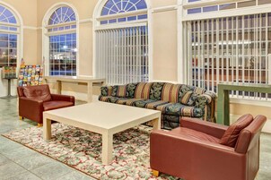 Un hall con un sofá, dos sillones, una mesa de centro y una alfombra estampada.