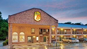 Un motel de type Super 8 avec une façade en briques, de nombreux balcons et un parking rempli de voitures.