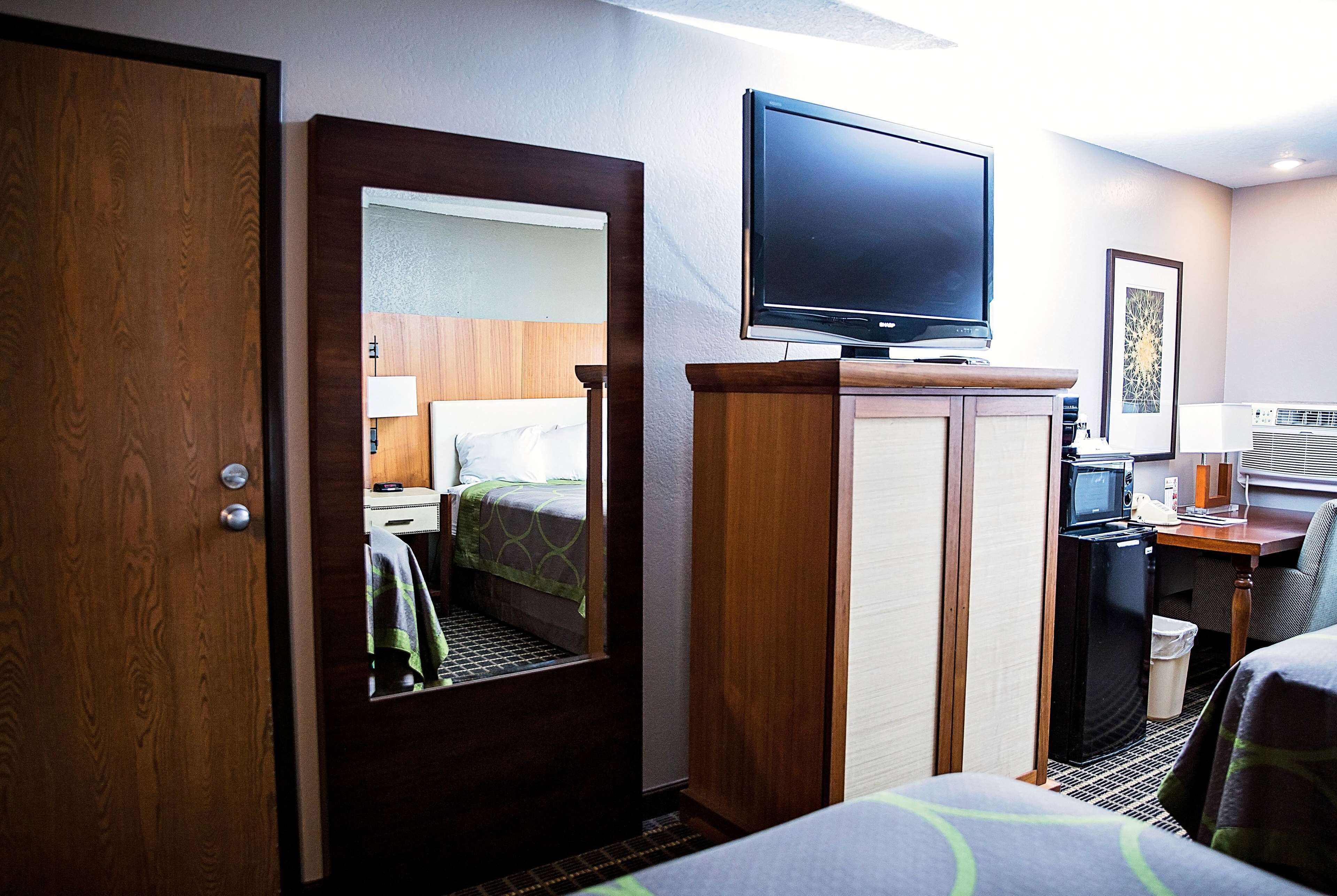 A hotel room with a bed, a television, a desk with a computer, and a microwave.