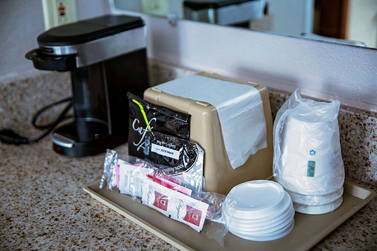 A tray with a coffee maker, a small refrigerator, and packaged food items.