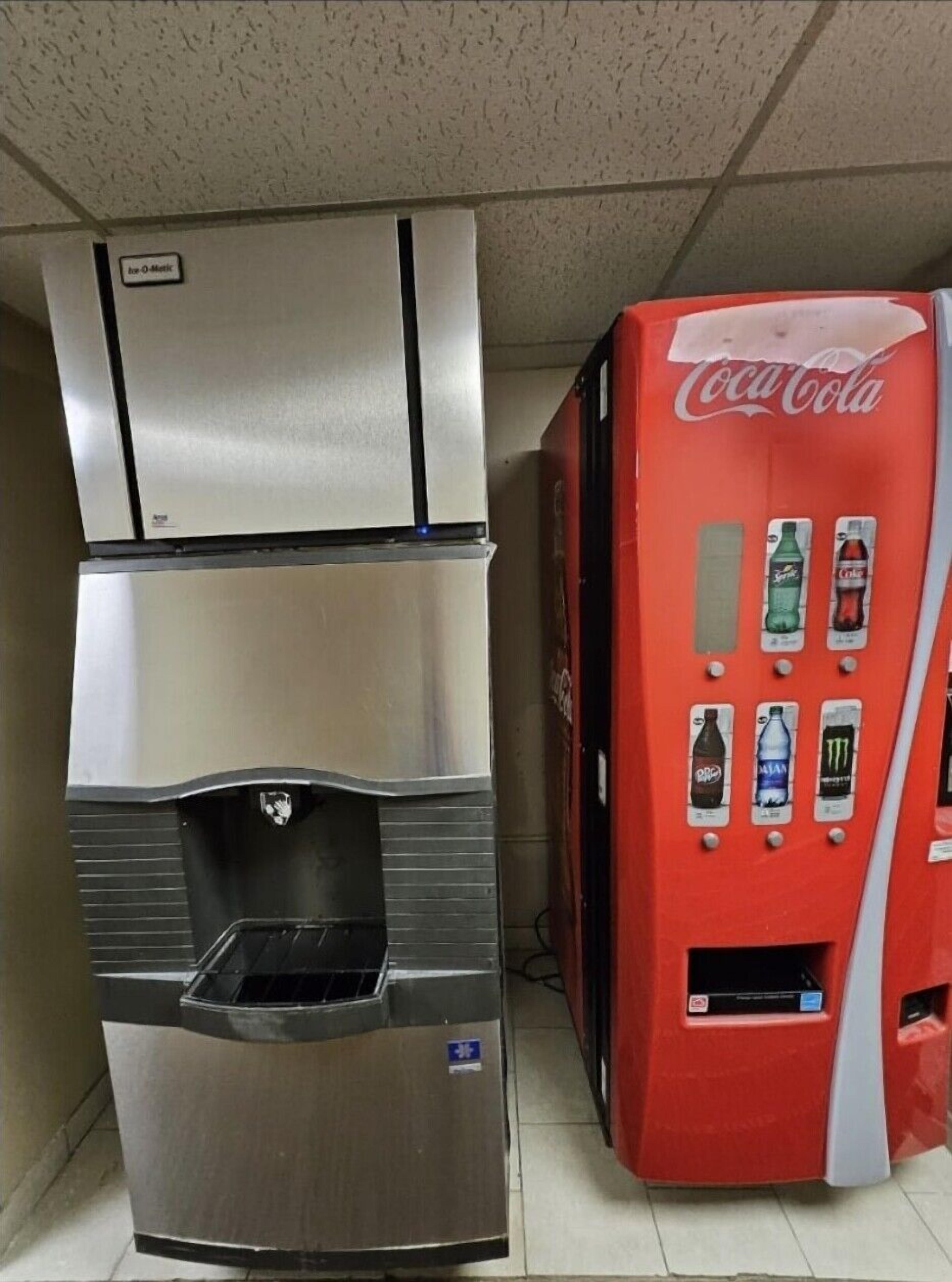A vending machine with Coca-Cola and a stainless steel refrigerator.