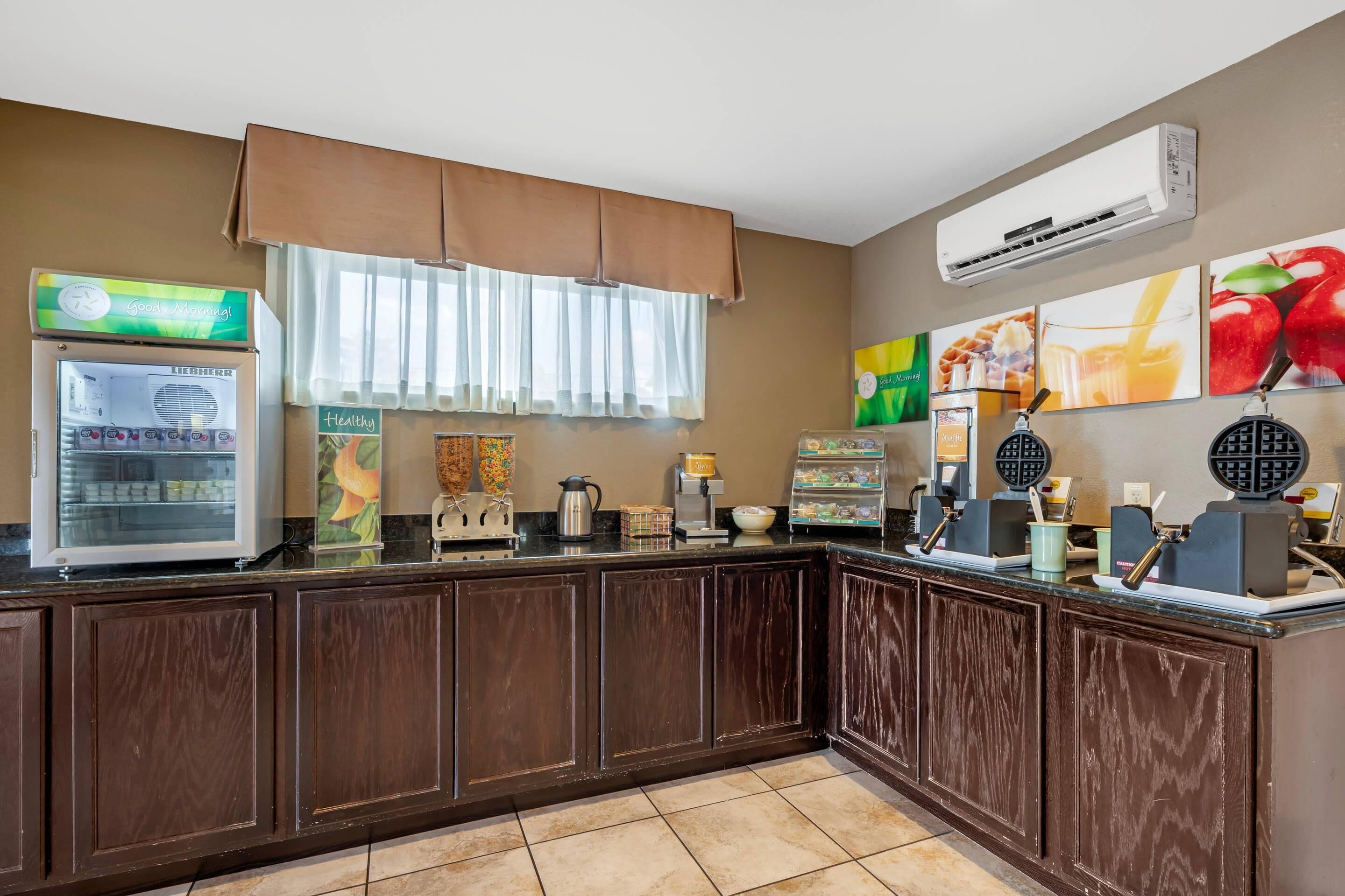 A kitchen area with a coffee machine, waffle maker, and a refrigerator.