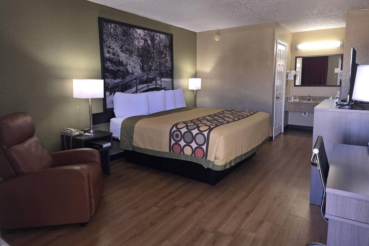 Une chambre d’hôtel comprenant un lit, un bureau, une chaise, un grand tableau et une salle de bain.