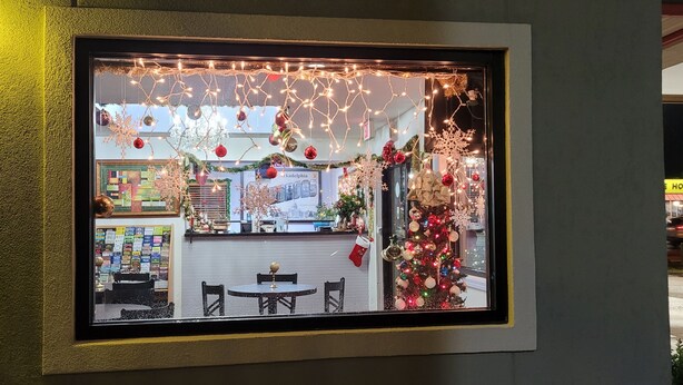 Vista enmarcada de un espacio interior decorado, con un árbol de Navidad, zona de estar y una barra con artículos a la vista.