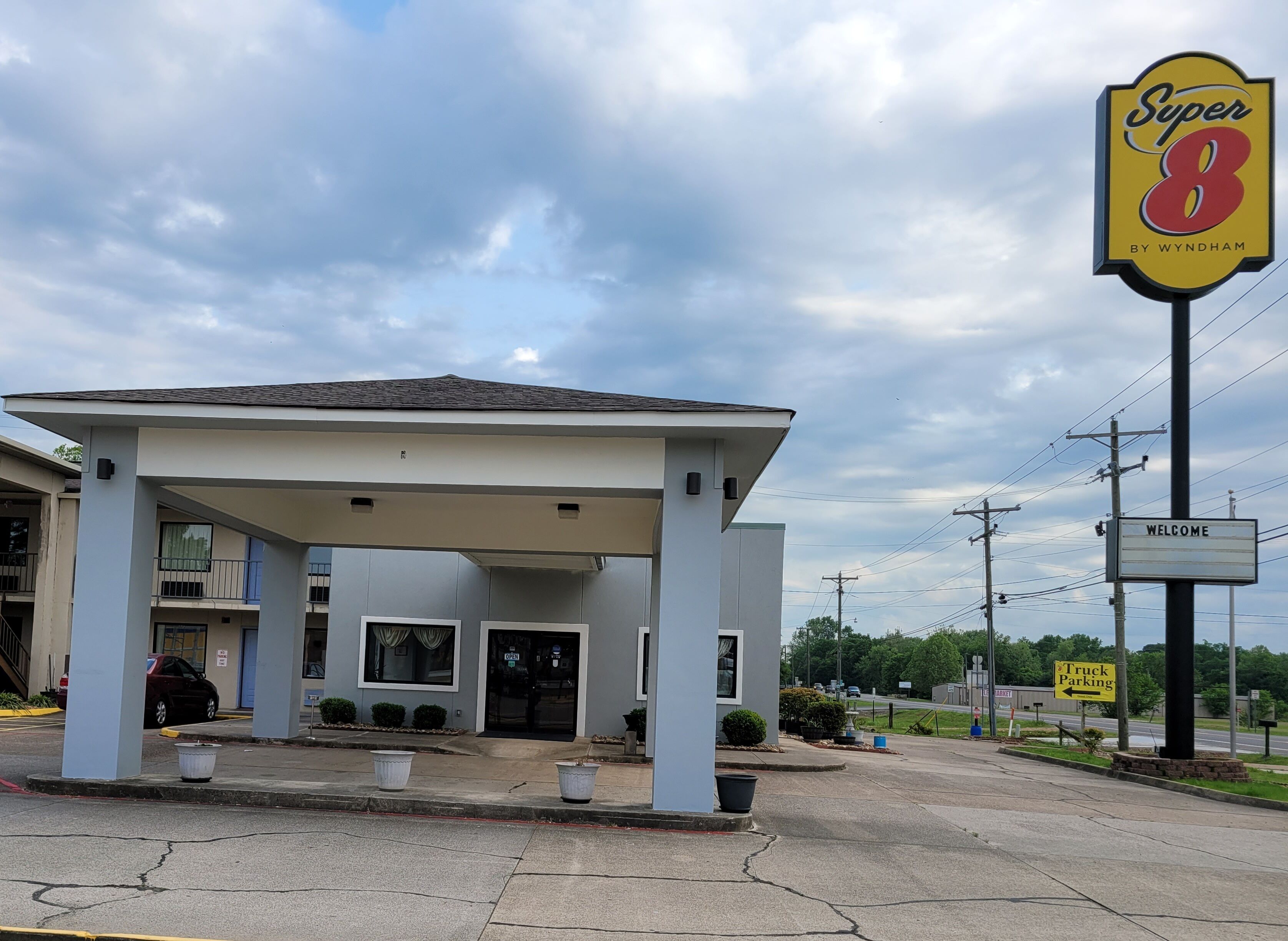 A Super 8 motel with a covered entrance, a welcome sign, and a truck parking sign.