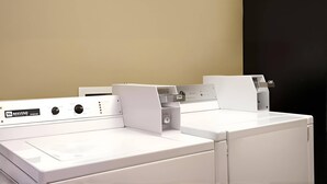 A row of white washing machines in a commercial setting. - Rodeway Inn & Suites Chandler - Phoenix South I-10 (Chandler)