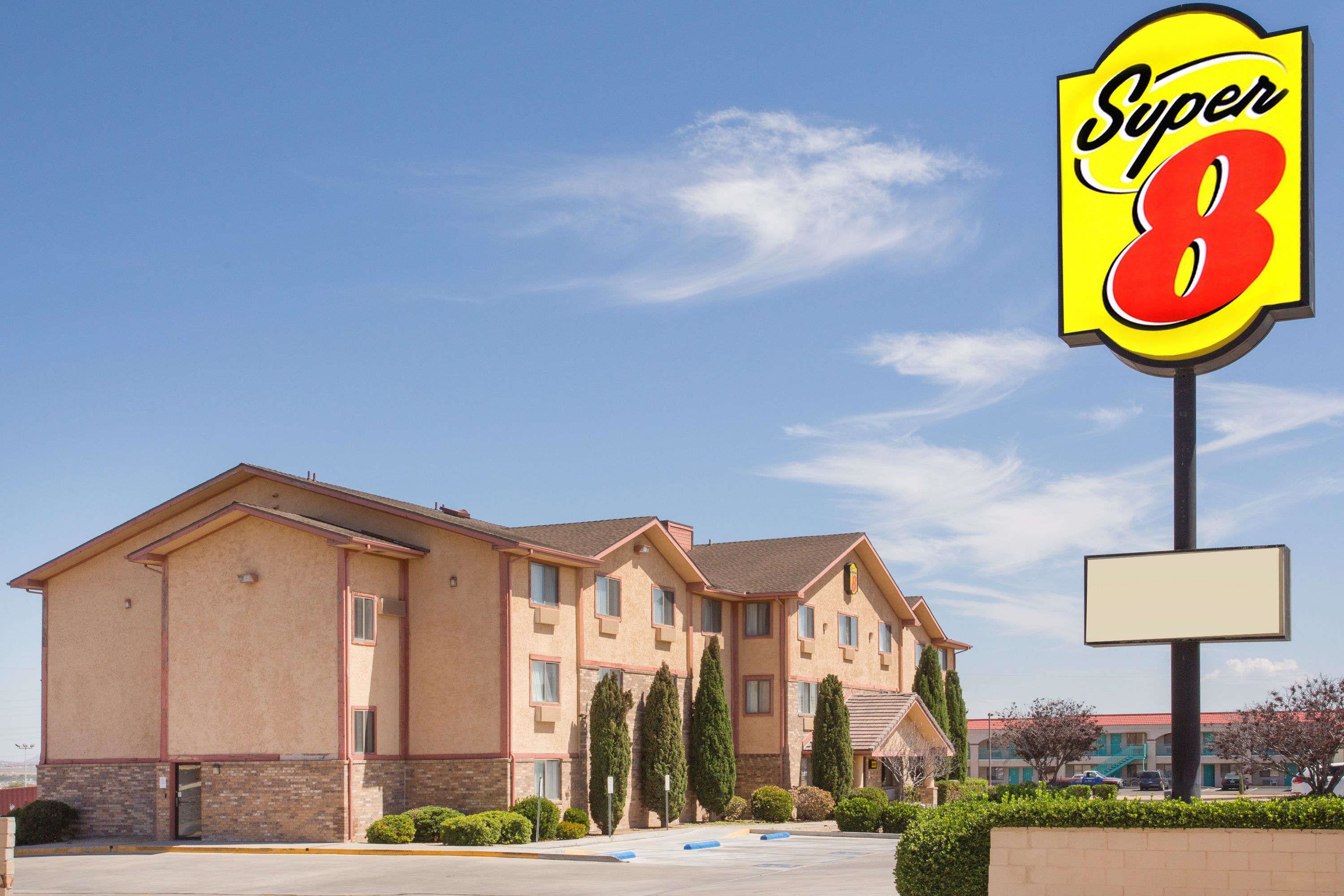 A hotel with a Super 8 sign, featuring a brick facade, multiple windows, and a parking lot.