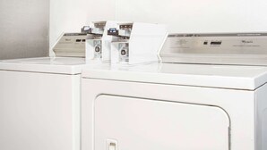 Una hilera de lavadoras Whirlpool de uso comercial y alta resistencia en un cuarto de lavado limpio con paredes blancas.