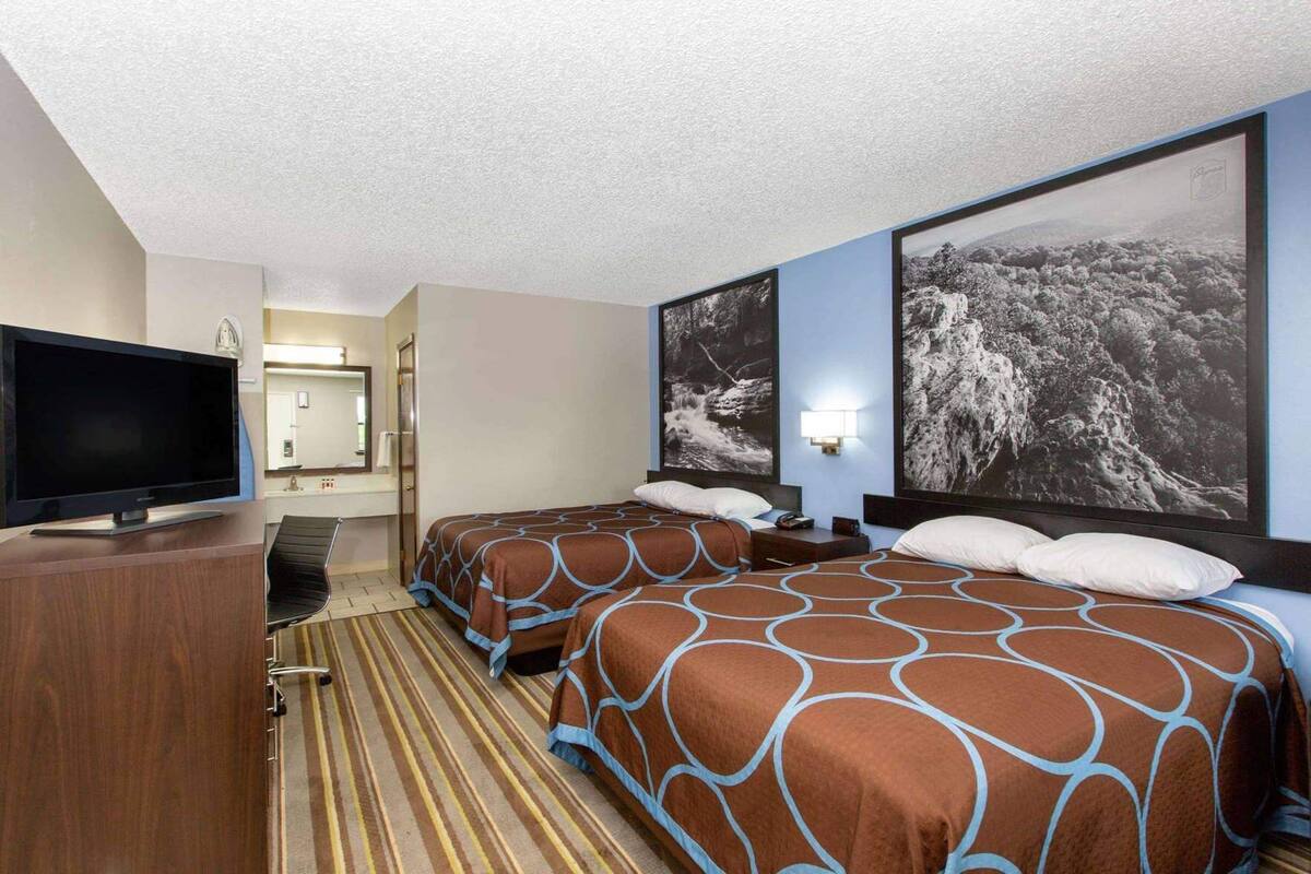 Une chambre d’hôtel avec deux lits, une télévision, une salle de bain et une grande fenêtre donnant sur la montagne.