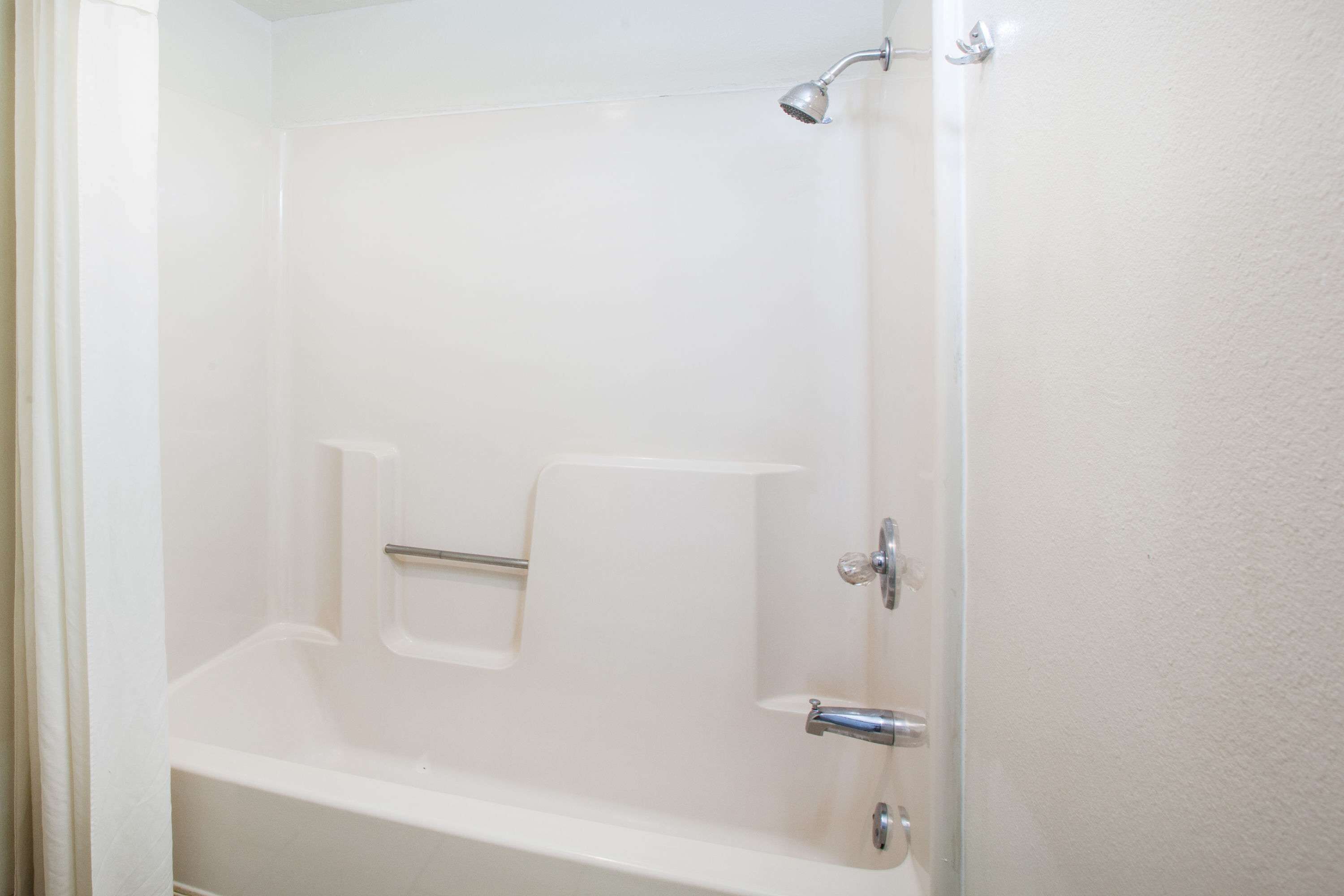 A white bathtub with a showerhead, a towel rack, and a soap dish.