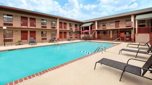 A hotel with a swimming pool, multiple balconies, and outdoor seating areas.