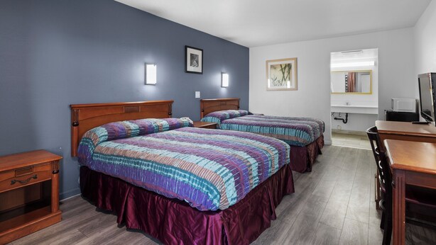 A hotel room with two beds, a wooden desk, a mirror, and a television. - Travel Inn - In Phoenix (Alhambra) (Phoenix)