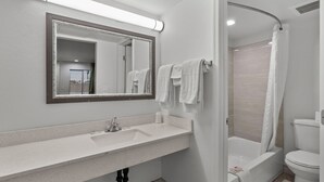 A modern bathroom with a large mirror, a sink, a toilet, and a shower area. - Travel Inn - In Phoenix (Alhambra) (Phoenix)