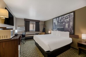 A hotel room with a large bed, a desk with a microwave, a TV, and a large window with curtains. - SureStay Hotel by Best Western Williams - Grand Canyon (Williams)