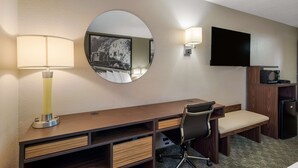 A hotel room with a wooden desk, a chair, a mirror, a flat-screen TV, a lamp, and a refrigerator. - SureStay Hotel by Best Western Williams - Grand Canyon (Williams)