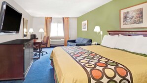 Una habitación de hotel con una cama, un escritorio, una silla, un televisor y una ventana con cortinas.